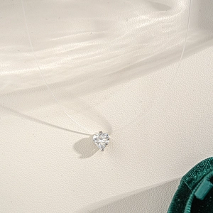 Floating heart moissanite necklace with invisible fishing line on a textured background