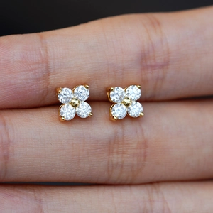 Rose gold clover earrings with D color moissanite stones held between fingers