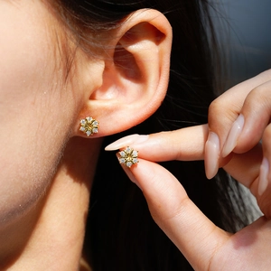 Elegant gold flower stud earrings with moissanite petals worn on ear for women