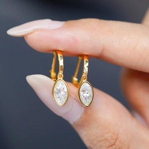 Macro detail of gold marquise-cut moissanite drop earrings held by hand for scale