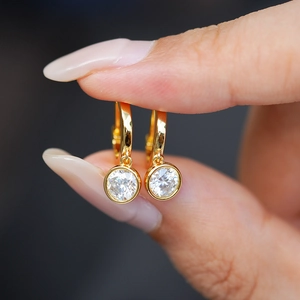 Detailed view of gold plated S925 silver huggie earrings with bezel set round moissanite