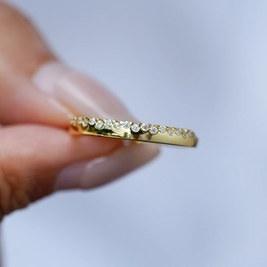 Dettaglio di un anello in argento S925 dorato con pietre moissanite tenuto in mano