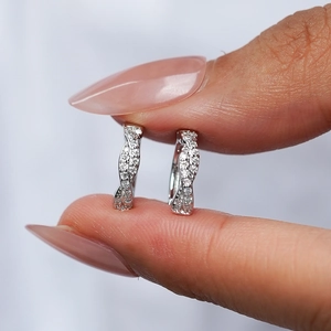 Main tenant des boucles d'oreilles créoles en argent 925 avec design torsadé et moissanite