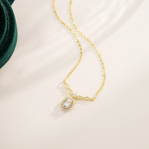 Detail view of oval moissanite pendant with sparkling diamond halo on gold silver chain
