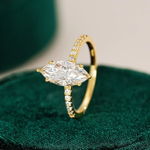 Close-up of marquise cut moissanite ring with side pavé diamonds on green velvet