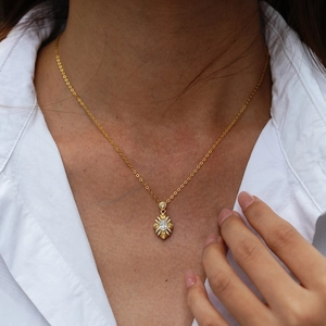 Elegant gold flower pendant necklace with central stone and moissanite halo on model