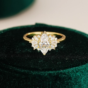 Macro shot of marquise cut moissanite ring in gold setting on green velvet box