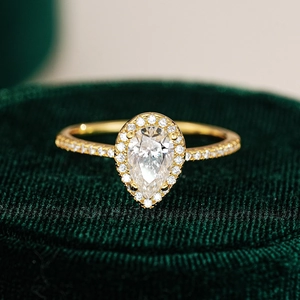 Bague moissanite taille poire en or jaune 18K sur un coffret à bijoux en velours vert
