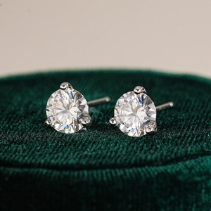 Macro shot of 925 silver moissanite stud earrings in a three-prong setting on velvet