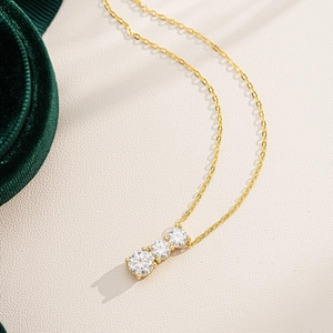 Detailed close-up of a three-stone moissanite pendant necklace on beige leather