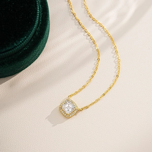 Macro shot of gold square halo pendant necklace on premium green velvet jewelry box