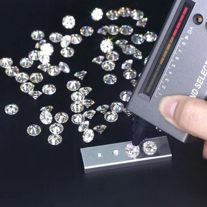 Sparkling 1 carat round moissanite loose stones being tested with a thermal diamond tester