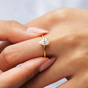 Pear cut moissanite engagement ring in 18K gold plated silver on a female hand