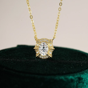 Gold oval moissanite pendant necklace in 925 silver on green velvet display