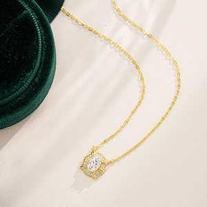 Macro detail of oval moissanite pendant with sparkling halo on gold chain necklace