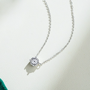 Dettaglio del ciondolo in zircone da 1 carato con catena in argento 925 su pelle crema