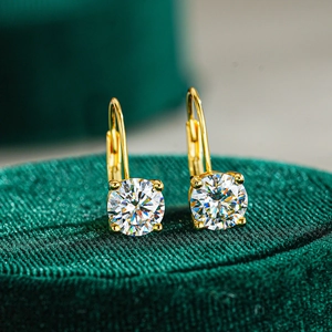 Macro view of gold plated moissanite leverback earrings in a green velvet jewelry box