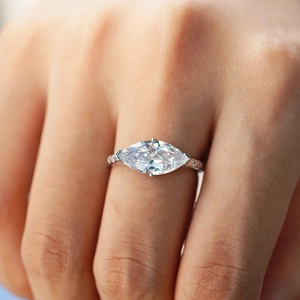 Close-up of a marquise cut moissanite engagement ring in s925 silver with side accent stones
