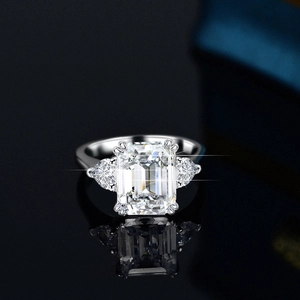S925 silver emerald cut moissanite ring with side pear stones on black mirror background