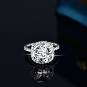 Luxury 5ct cushion-cut moissanite halo ring with pavé band on a black reflective surface
