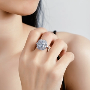 Elegant emerald cut moissanite ring with a double halo and pave band on a finger