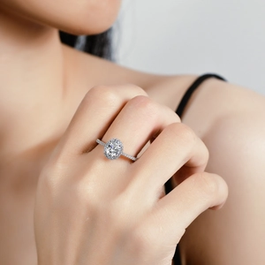 Oval cut moissanite engagement ring with halo design on a model hand
