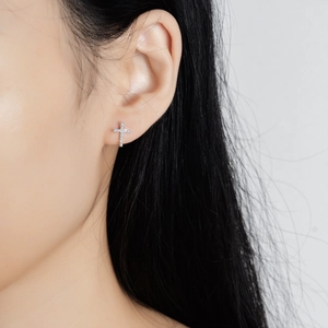 Close-up of s925 silver cross stud earrings with sparkling stones on model ear