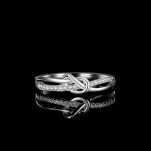 Infinity knot S925 sterling silver ring with pavé moissanite on a black reflective surface