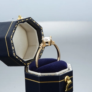 Moissanite ring in crown setting with side stones and blue velvet jewelry box