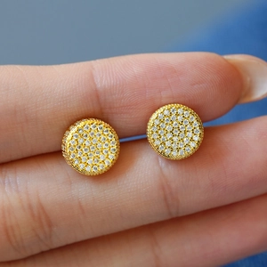 Detailed close-up of gold-plated cylinder stud earrings with sparkling pave-set stones