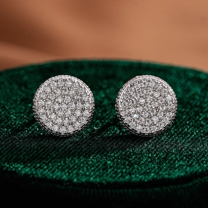 Macro shot of silver round halo stud earrings with micro-pave crystals on green velvet