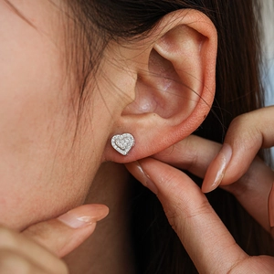 Icy heart-shaped 925 sterling silver moissanite stud earrings on a model's ear