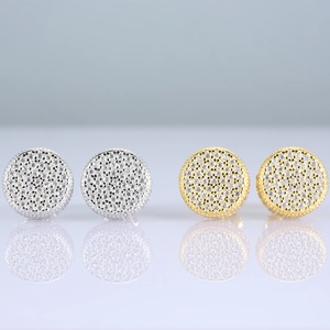 Macro shot of silver and gold iced out stud earrings with round micro-paved moissanite stones