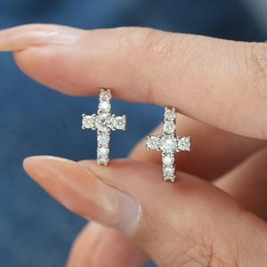 Gros plan de boucles d'oreilles croix en argent S925 avec moissanite sur un doigt