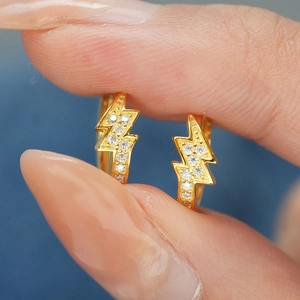 Gros plan sur des boucles d'oreilles éclair dorées serties de moissanites