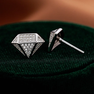 Close-up of diamond-shaped S925 silver stud earrings with pavé moissanite on green velvet