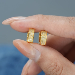 Vue détaillée de boucles d'oreilles créoles dorées avec quatre rangées de pavage