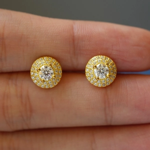 Orecchini a perno in moissanite tondi dorati con doppio halo mostrati sulla mano