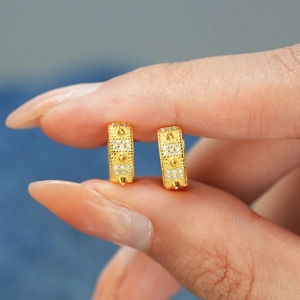 Vue macro de boucles d'oreilles huggie en argent S925 doré avec clous et moissanite