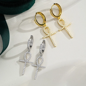 Close-up of gold and silver Ankh cross earrings with pavé moissanite stones