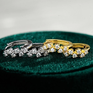 Vue macro de boucles d'oreilles moissanite dorées et argentées sur velours vert