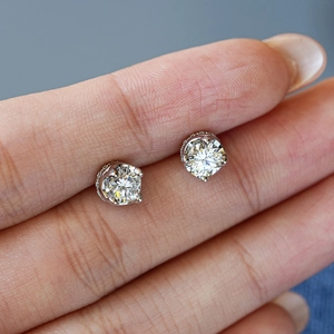Classic round brilliant cut moissanite silver stud earrings shown between fingers