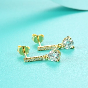 Macro shot of S925 silver moissanite earrings with gold plating and tassel detail
