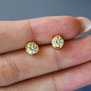 Macro view of classic four-prong moissanite stud earrings in gold-plated silver setting