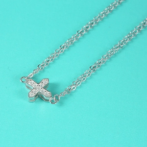 S925 sterling silver cross necklace with pavé moissanite stones on a blue background
