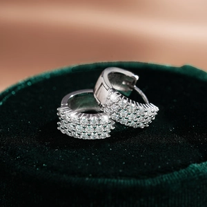 Gros plan de créoles en argent 925 avec moissanite et serti pavé sur velours vert