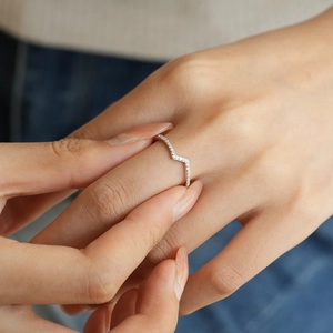 Gros plan d'une bague en argent en forme de V avec des pierres pavées étincelantes