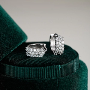 Boucles d'oreilles huggie en argent 925 et moissanite sur écrin en velours vert