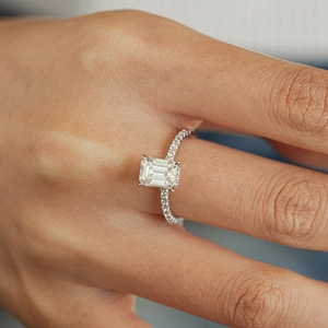 Detailed macro of 1 carat emerald cut rectangle moissanite ring with pavé silver band