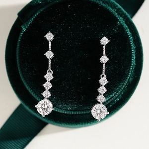 Macro view of 925 silver moissanite earrings with gradient stones on green velvet